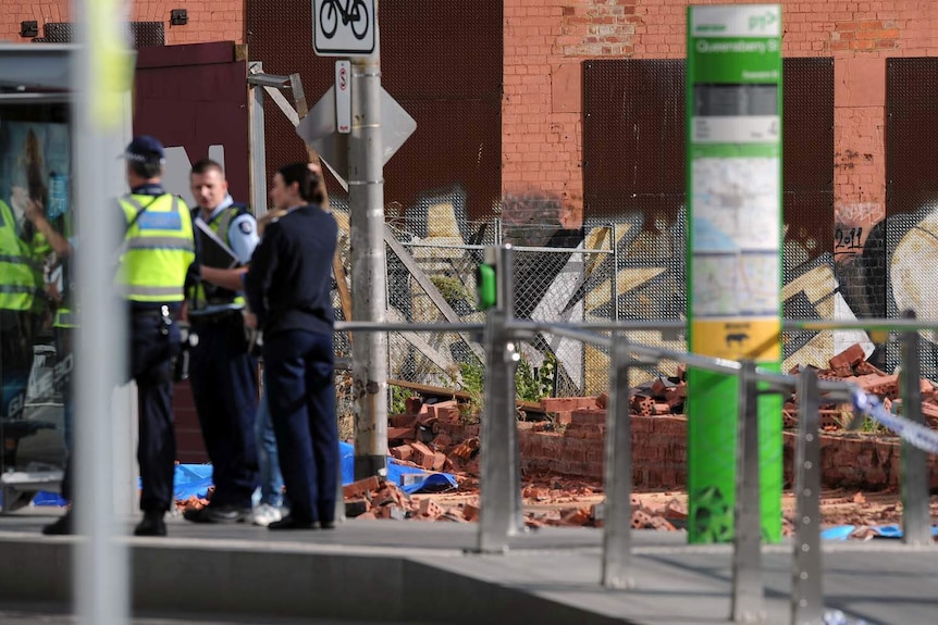 Police stand near the scene of a fatal wall collapse