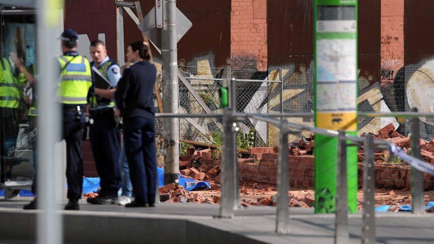 Police stand near the scene of a fatal wall collapse