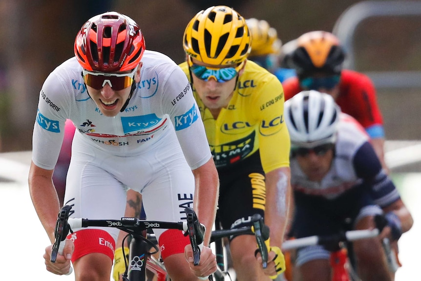 Tadej Pogacar grimaces and rides in a white jersey in front of Primoz Roglic who is in a yellow jersey