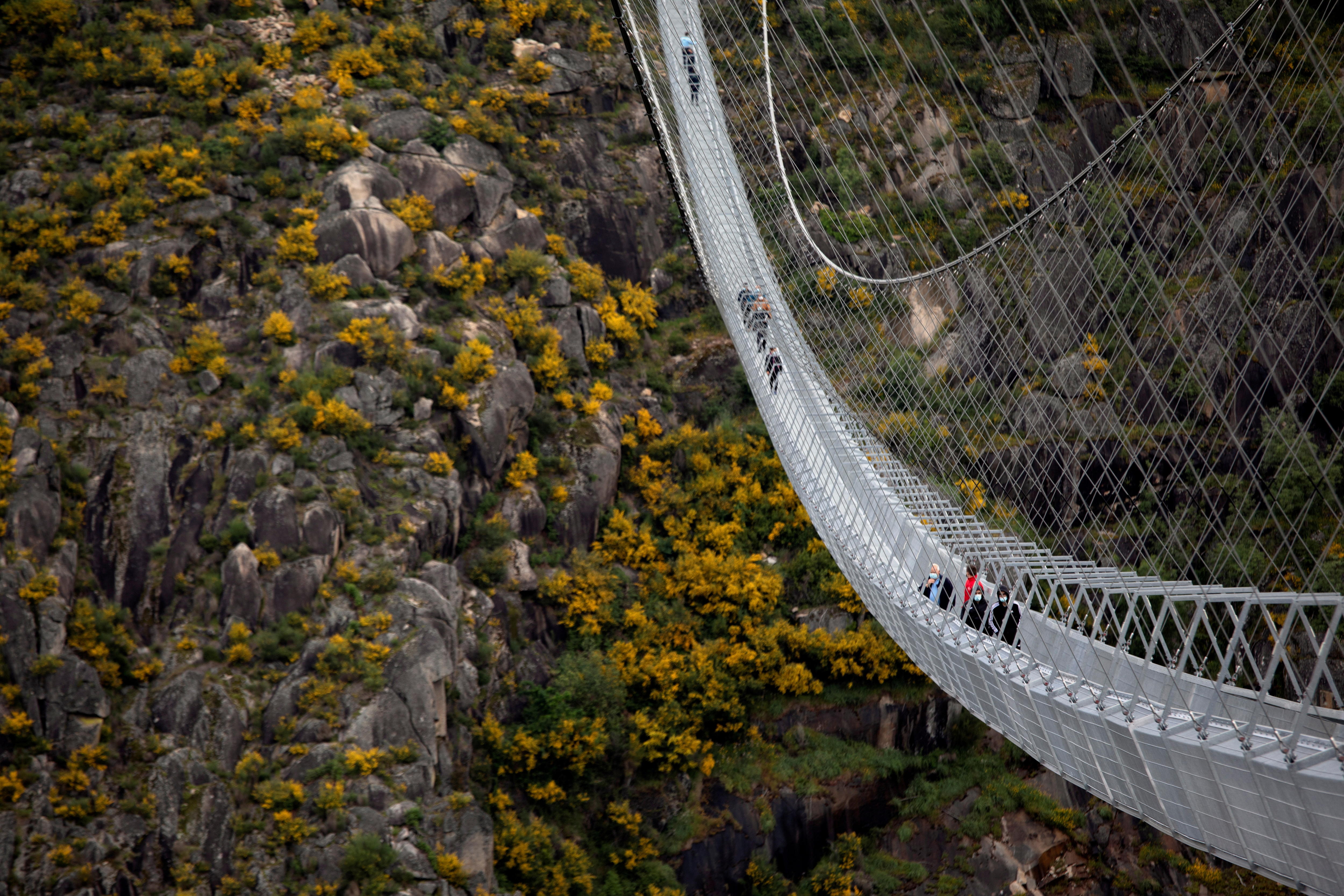 People walking along a suspension bridge high above a valley.