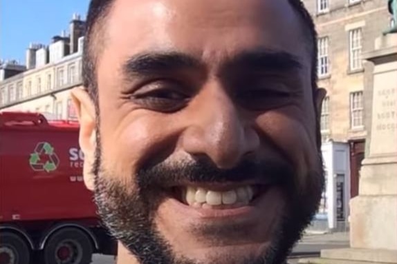 A man with a bear grins for a selfie outside a building in London 