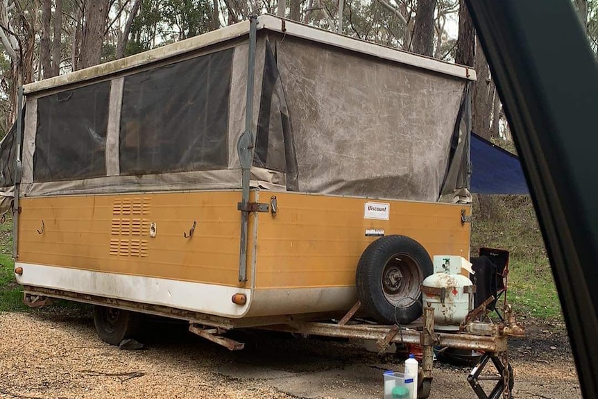 A run down yellow van in the bush. 