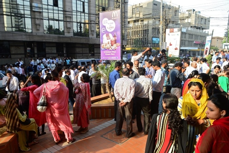 People stand outside buildings in Pakistan after powerful earthquake