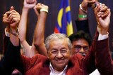 Mahathir Mohamad raises his arms at a press conference