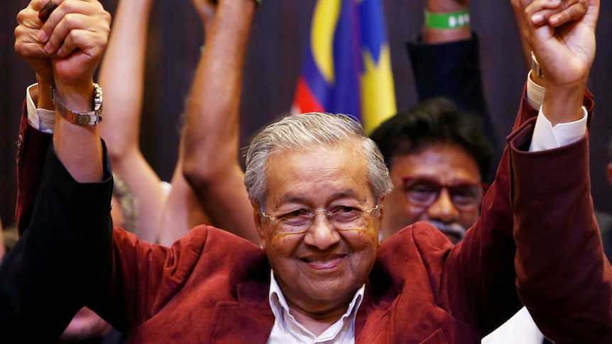 Mahathir Mohamad raises his arms at a press conference