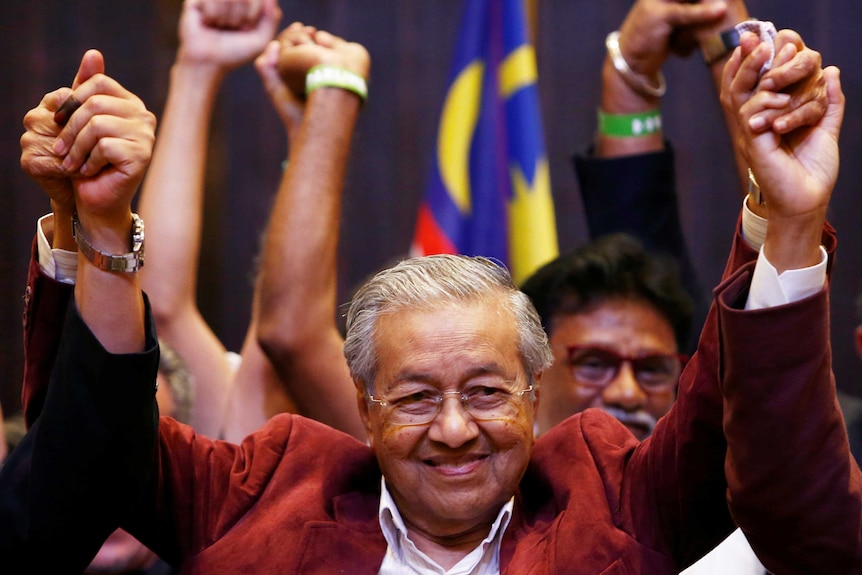 Mahathir Mohamad raises his arms at a press conference