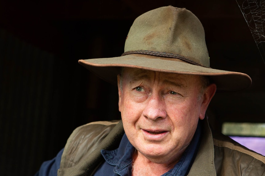 Tight portrait of an ageing man in bush hat looking past the camera.