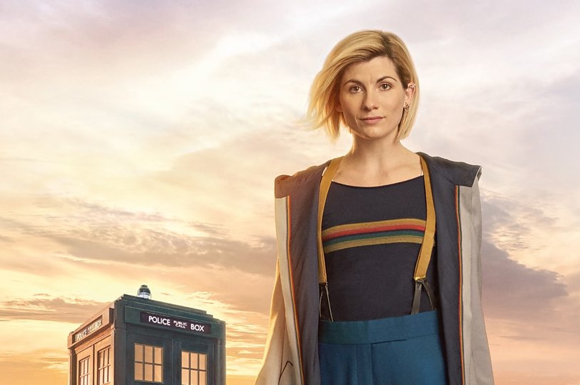 Jodie Whittaker as the 13th Doctor, standing in front of the TARDIS.
