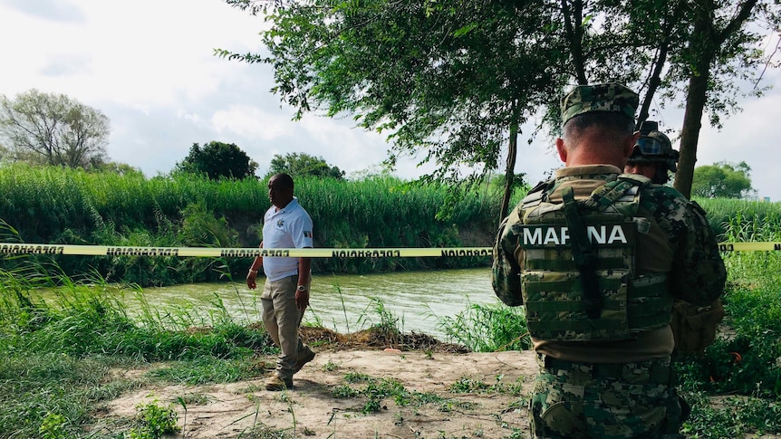 Mexican authorities walk along the Rio Grande river bank where the bodies were found.