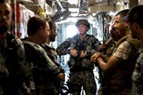 Australian and Saudi sailors in the corridor of a ship with one Australian posing for the camera