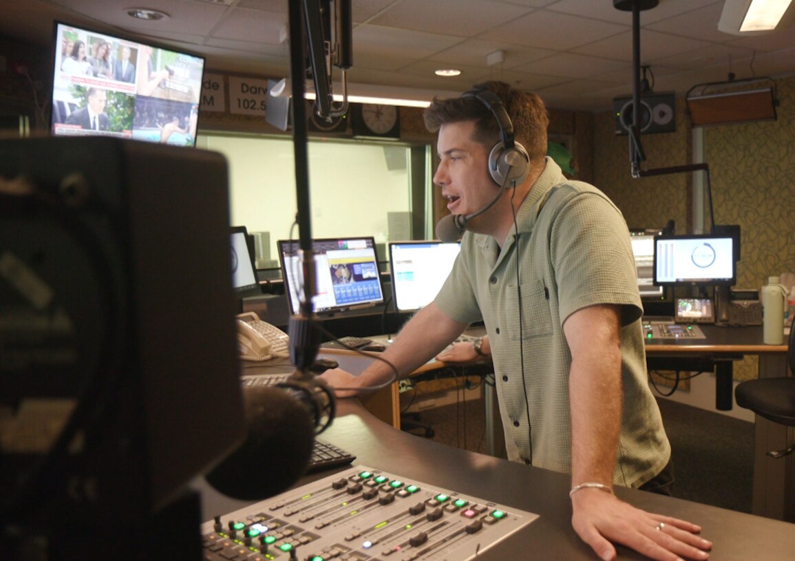 ABC Sport presenter Jared Coote wears a microphone headset and is speaking in a radio studio