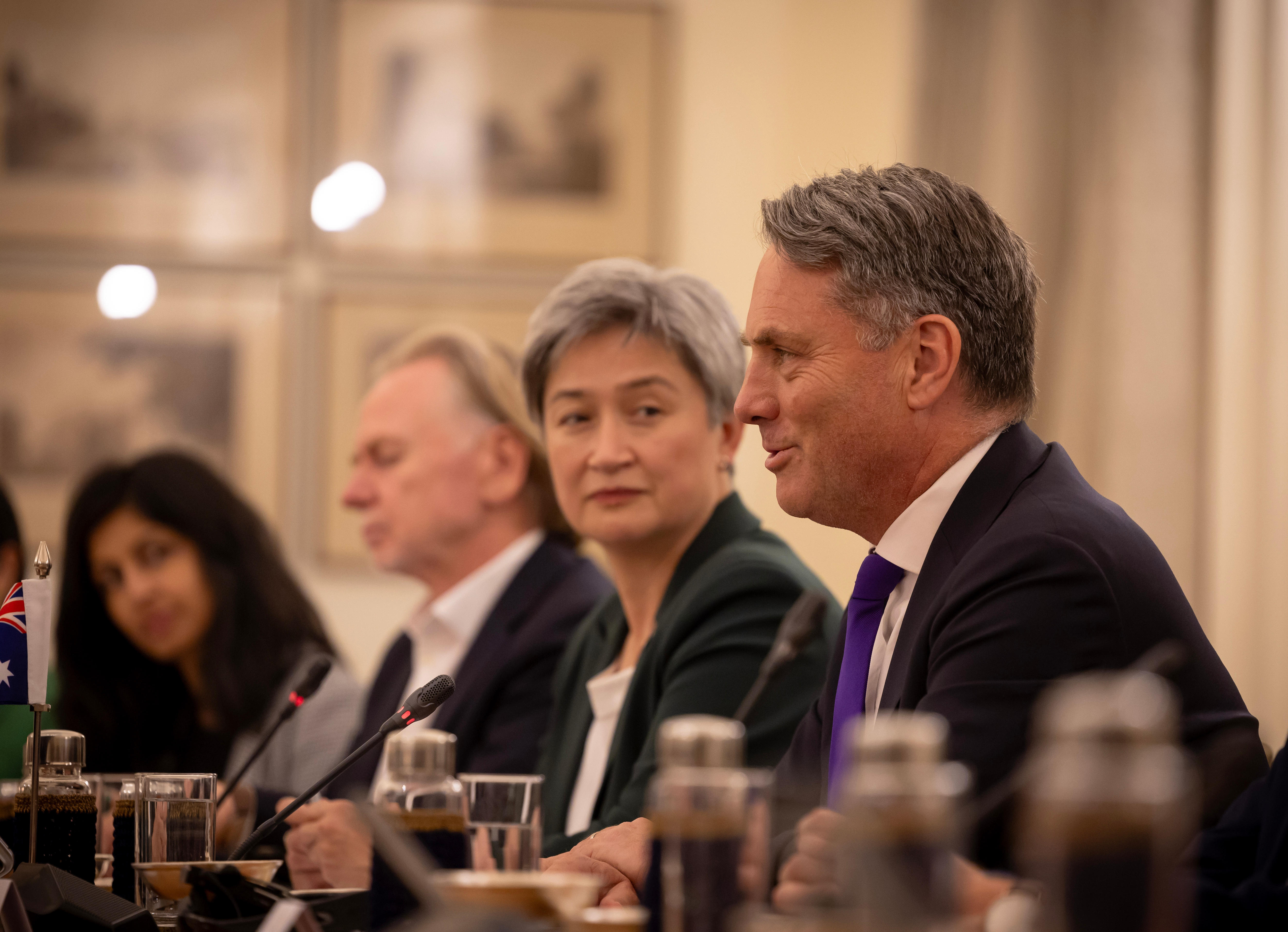 Richard Marles speaks, smiling, at an official meeting while Penny Wong looks on in the background