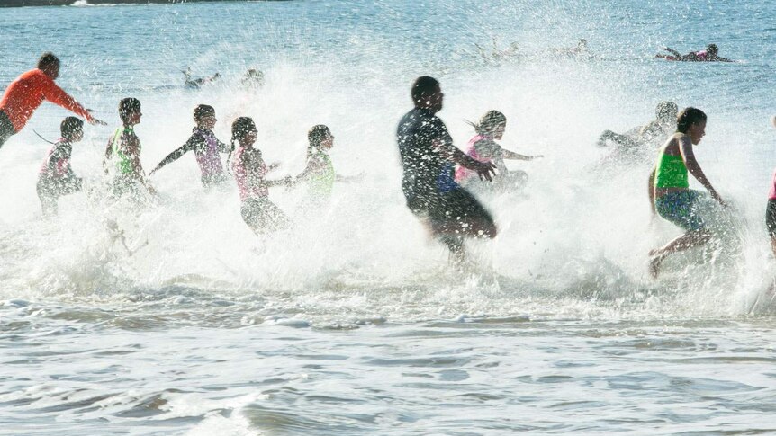 Chaotic splashing as a group of young lifesavers run from the ebach into the waves