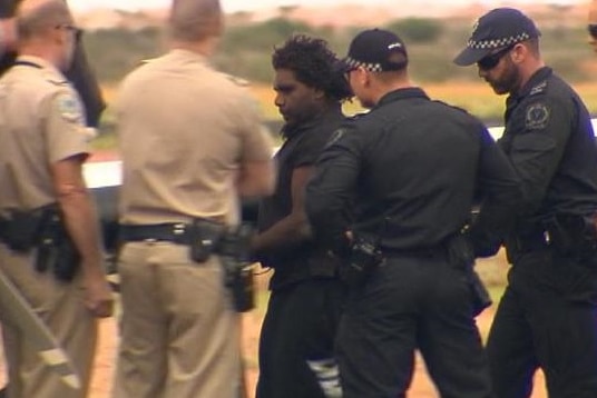 Dudley Davey handcuffed and surrounded by police.