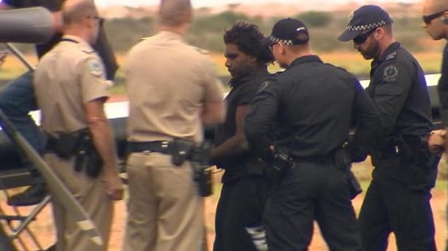 Dudley Davey handcuffed and surrounded by police.