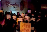 People hold signs during a candlelight vigil.