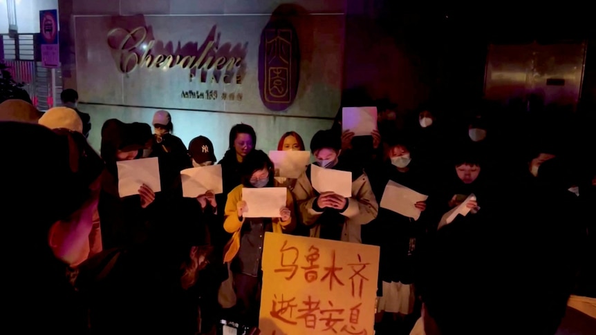 People hold signs during a candlelight vigil.