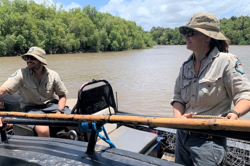 Two wildlife rangers on a boat in the Proserpine River. 