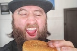 A man holds a McDonald's burger pretending to take a bite.