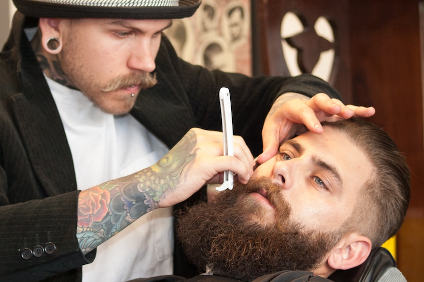 Ash Weller uses a traditional cut-throat razor to clean up the Tim Hutton's beard edges.