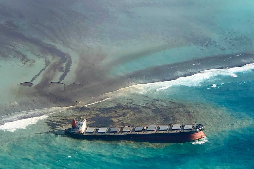 Oil leaks from a ship run aground on a reef.