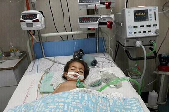 Toddler Youssef lies in a coma in a hospital bed connected to multiple machines.