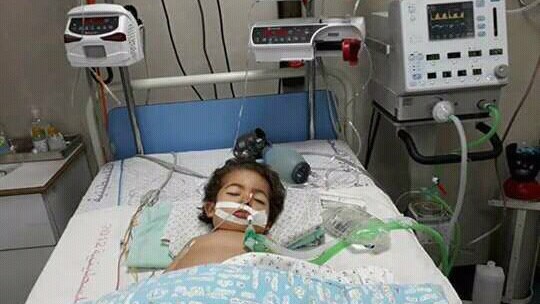 Toddler Youssef lies in a coma in a hospital bed connected to multiple machines.
