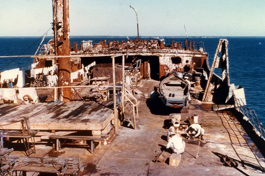 Japanese workers sit on the deck of recovered ship The British Motorist