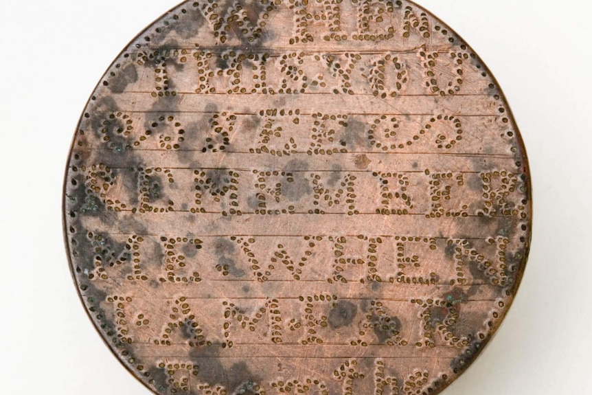 An old copper coin is shaved back and engraved with a message of love.