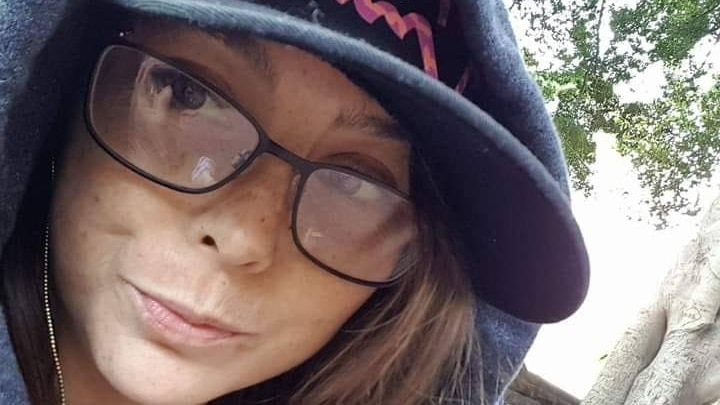 A close up photos of a woman in her 30's wearing her cap and hoodie 