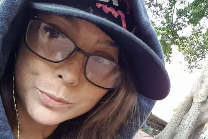 A close up photos of a woman in her 30's wearing her cap and hoodie 