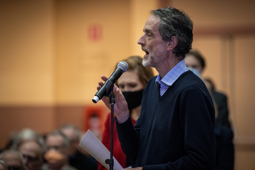 A middle-aged man speaks into a microphone