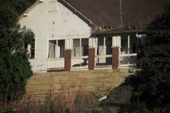 the exterior of a house with damaged fencing and dirty brick and woodwork