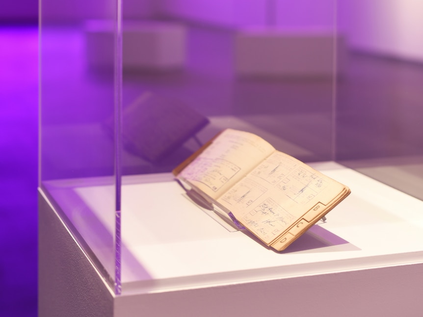 An old passbook sitting in a glass case in an art gallery.