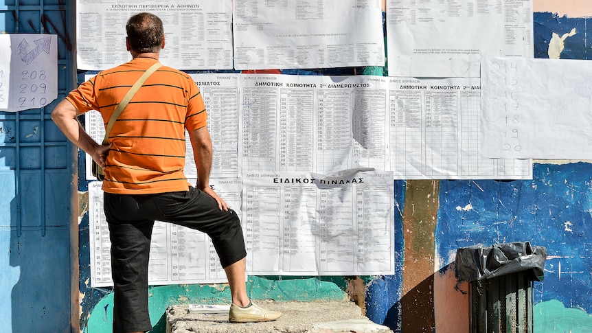 A man looks at electoral boards before casting his vote at a polling station in Athens on June 17, 2012.
