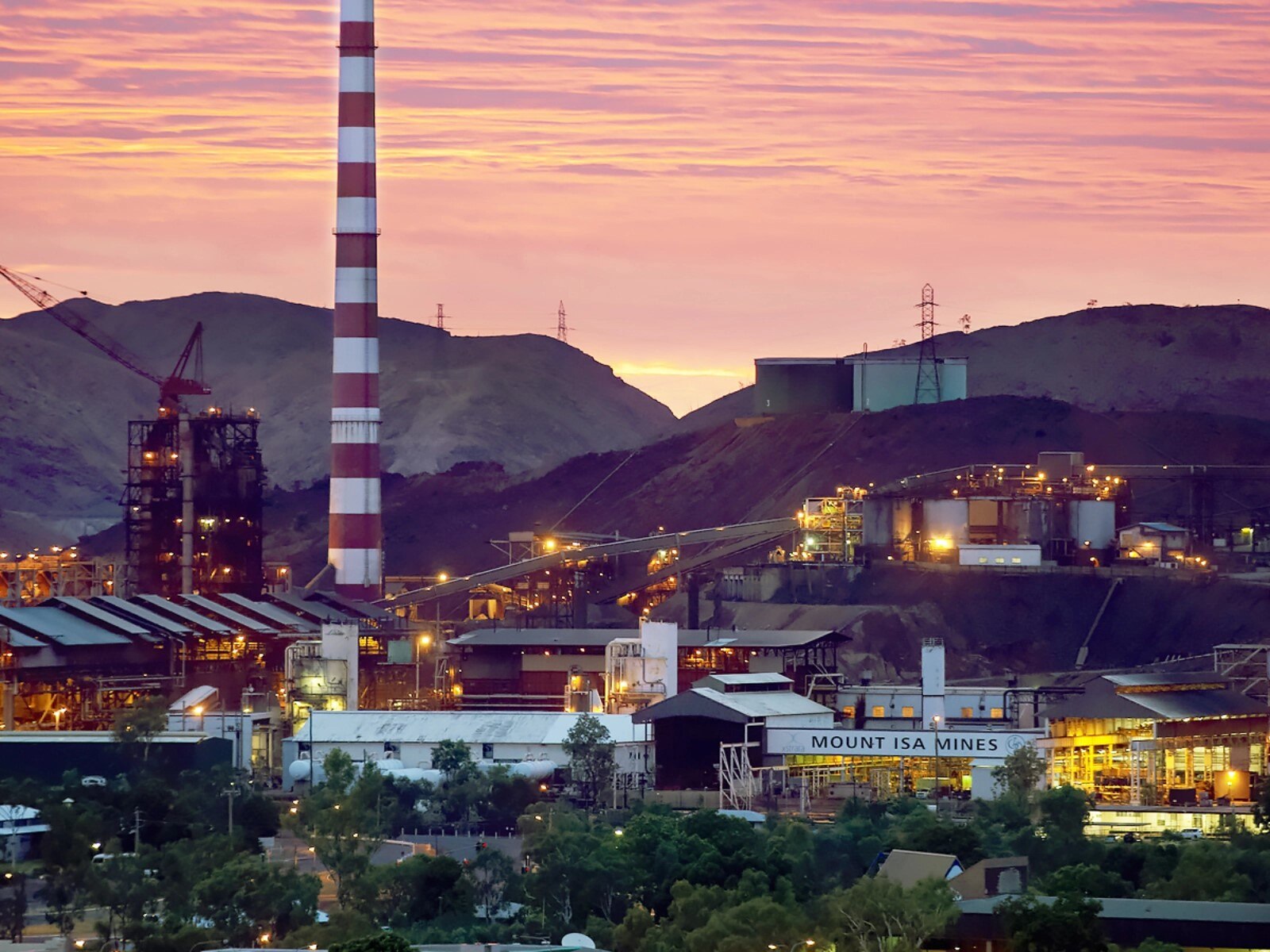 Sunset behind mining operation, candy cane coloured chimney