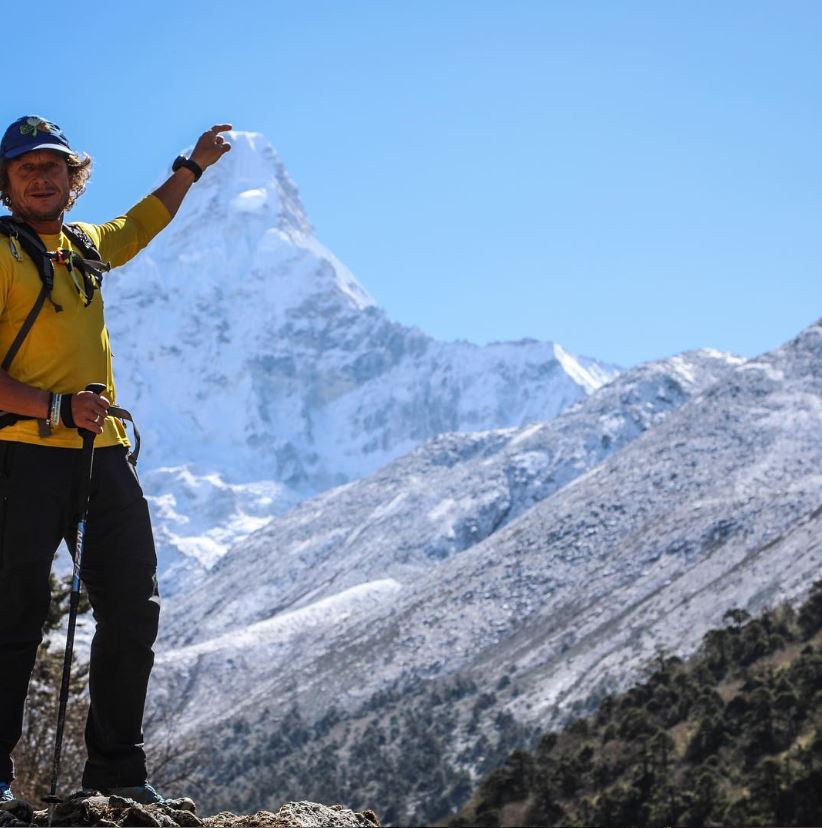 A man points at the top of a mountain.