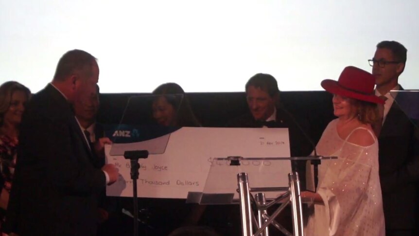 Gina Rinehart presents a Barnaby Joyce with a giant cheque on stage.