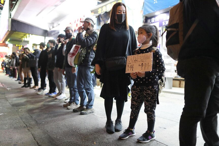Young girl holds sign with Cantonese writing in protest.