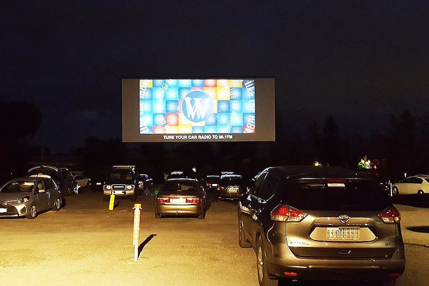 Cars in front of drive-in screen.