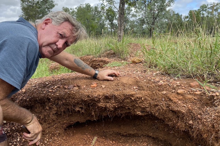 A man with grey hair digs at soil.