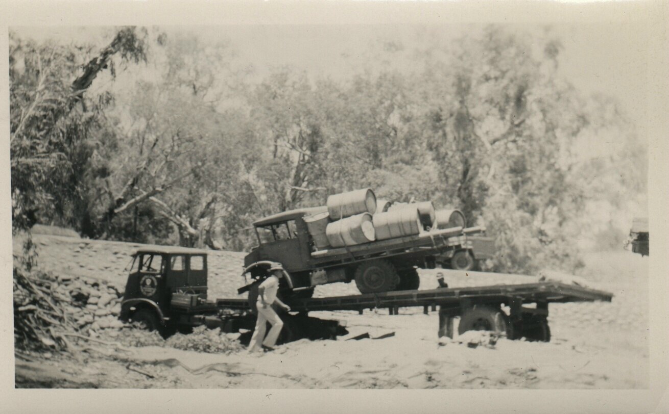 A black and white photo of an old truck bogged in a muddy road