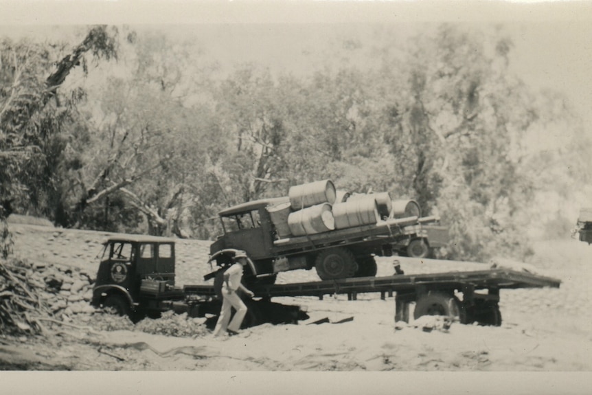 A black and white photo of an old truck bogged in a muddy road