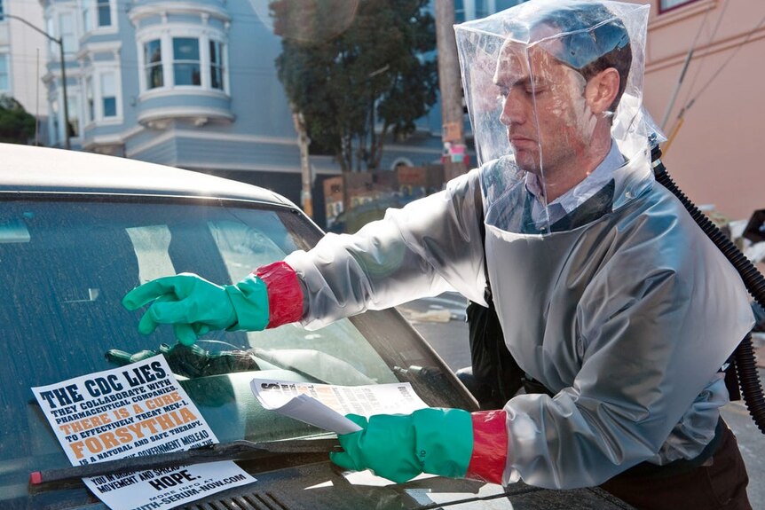 Contagion film still showing man put posters on car window.