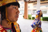 A close up of a young man wearing traditional dress standing at an entrance with another man.
