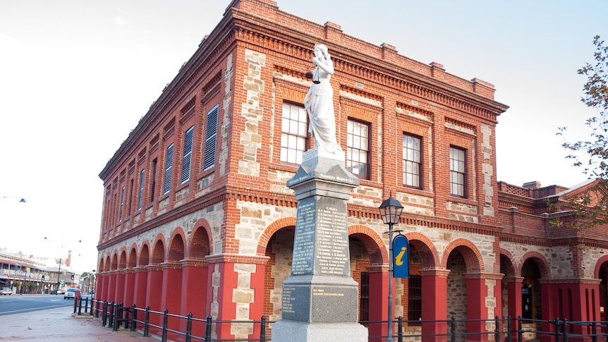 A two-storey brick building with a statue in the front.