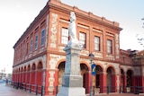 A two-storey brick building with a statue in the front.