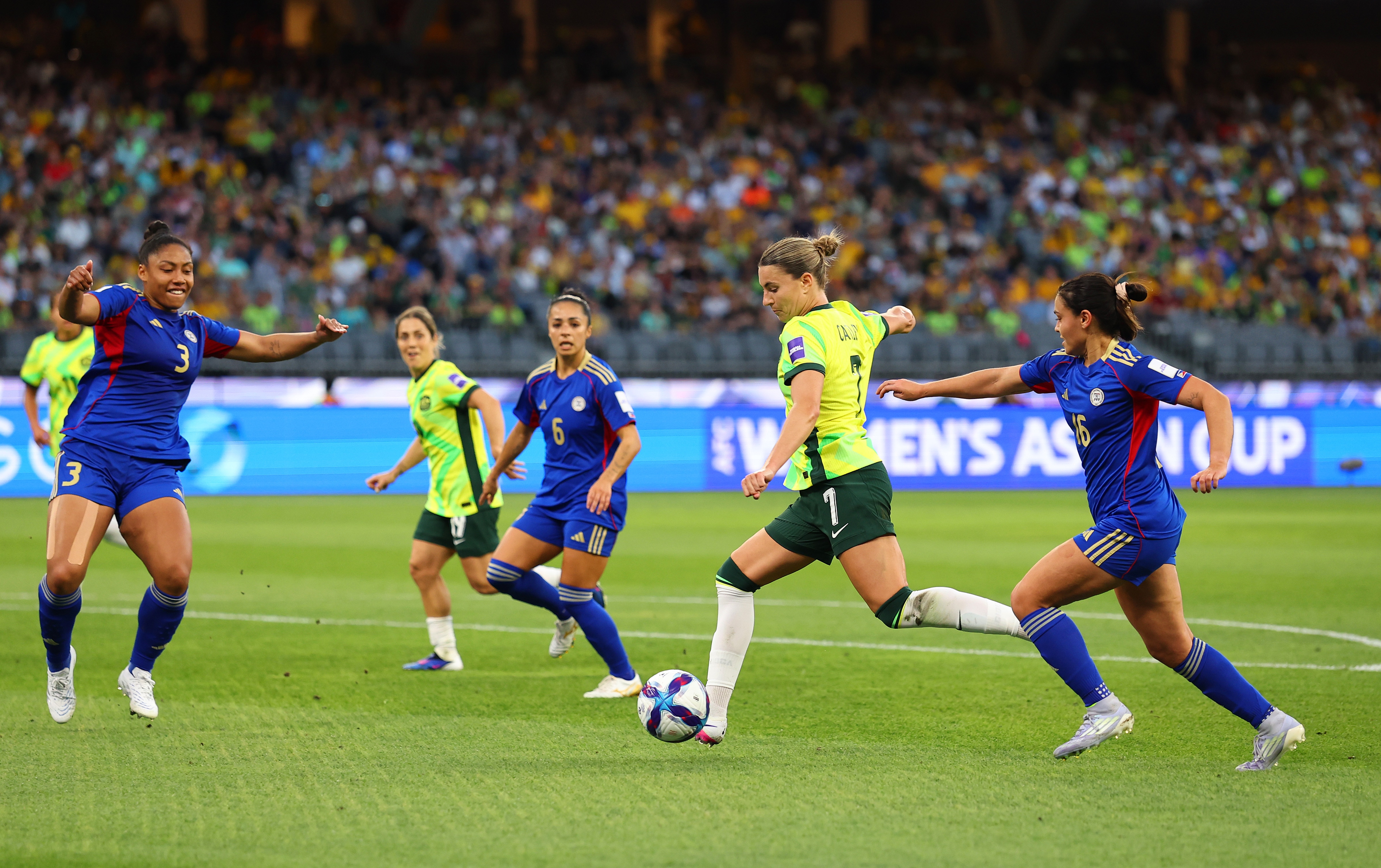 A jogadora do Matildas, Steph Catley, se prepara para chutar a bola durante um jogo, ela tem três defensores filipinos ao seu redor