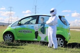 The Stink stands with arms crossed in front of Queensland Urban Utilities' poo-powered car