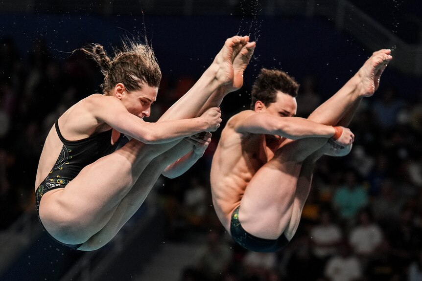 Domonic Bedggood and Maddison Keeney mid-dive, with their heads bent towards their knees as they fall through the air.